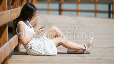 可爱的女人<strong>坐在公园里</strong>一边用手机看短信。